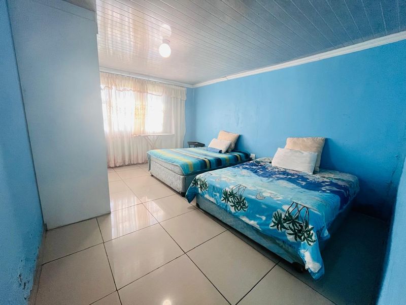 A bedroom featuring tiled flooring and a tongue and groove ceiling, currently configured with two beds.