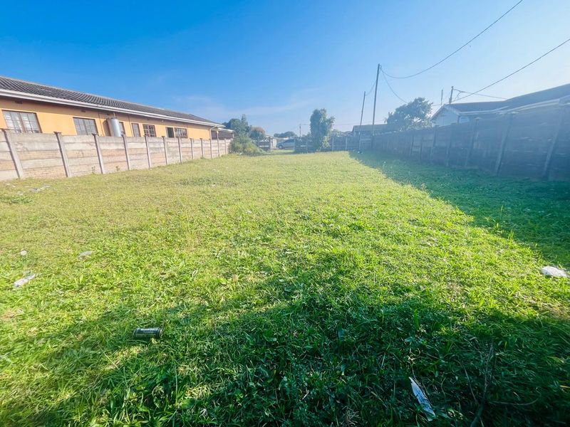 A vacant residential plot featuring a grassed surface enclosed by precast concrete boundary walls.