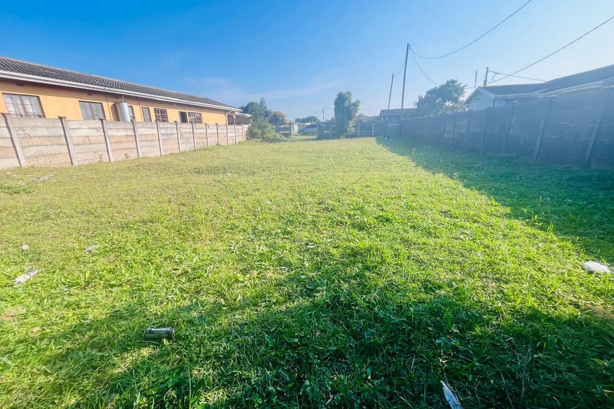 A vacant residential plot featuring a grassed surface enclosed by precast concrete boundary walls.