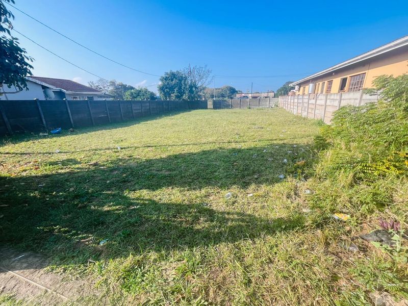 A vacant residential plot featuring a grass lawn enclosed by precast concrete boundary walls.