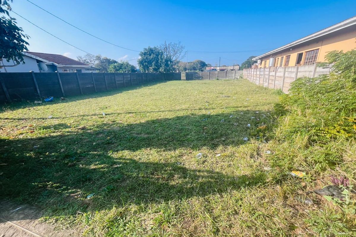 A vacant residential plot featuring a grass lawn enclosed by precast concrete boundary walls.