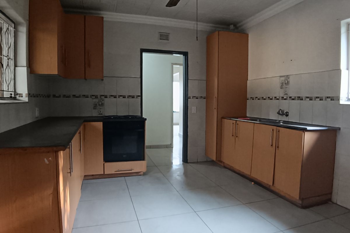 A functional kitchen featuring wooden cabinetry, built-in oven, double sink, and tiled flooring, offering a blank canvas for modern renovation.