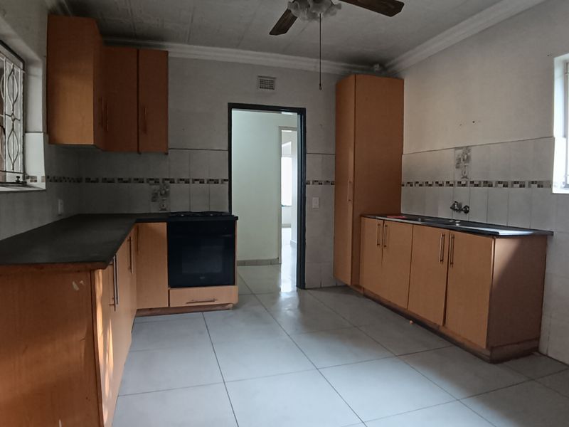 A functional kitchen featuring wooden cabinetry, built-in oven, double sink, and tiled flooring, offering a blank canvas for modern renovation.