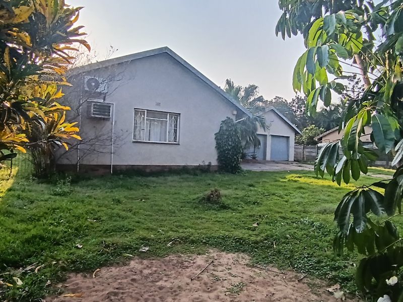 Rear view of the property featuring a lawn, double garage, and wall-mounted air conditioning unit.