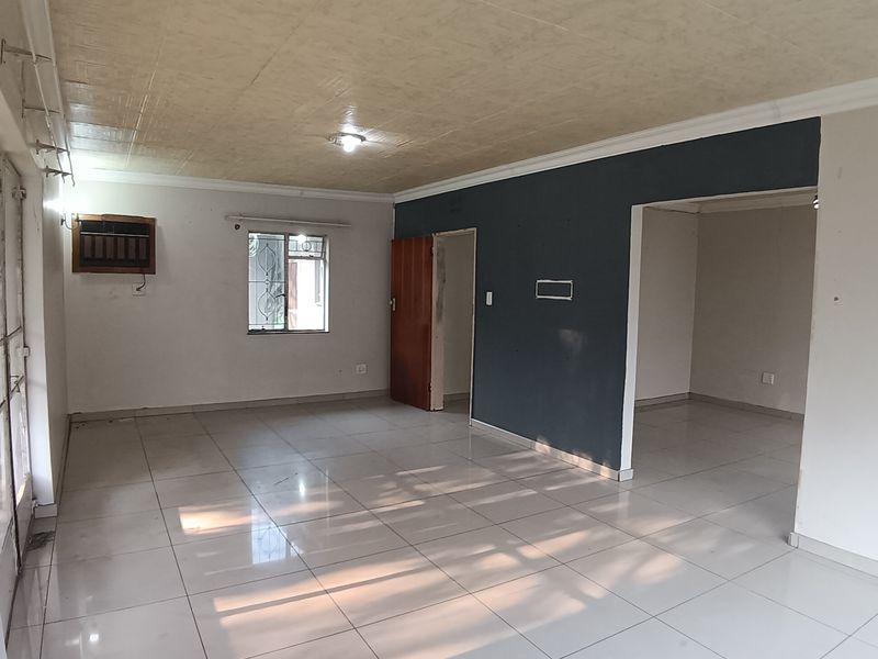 An open-plan living area featuring tiled flooring, an integrated air conditioning unit, and neutral wall finishes, offering a blank canvas for interior design.
