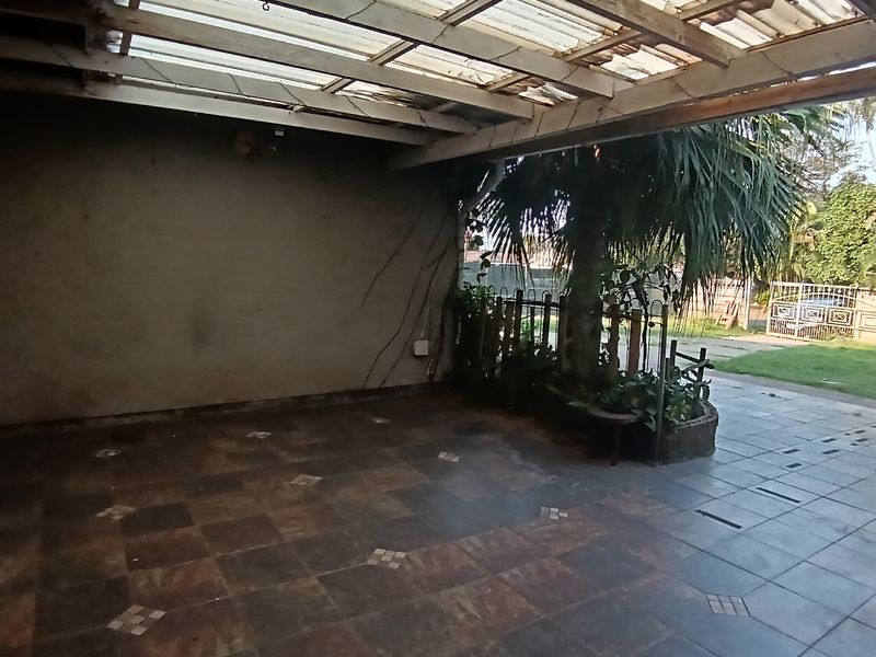 A covered outdoor patio area featuring tiled flooring and a translucent roof structure, providing a versatile space for outdoor living.