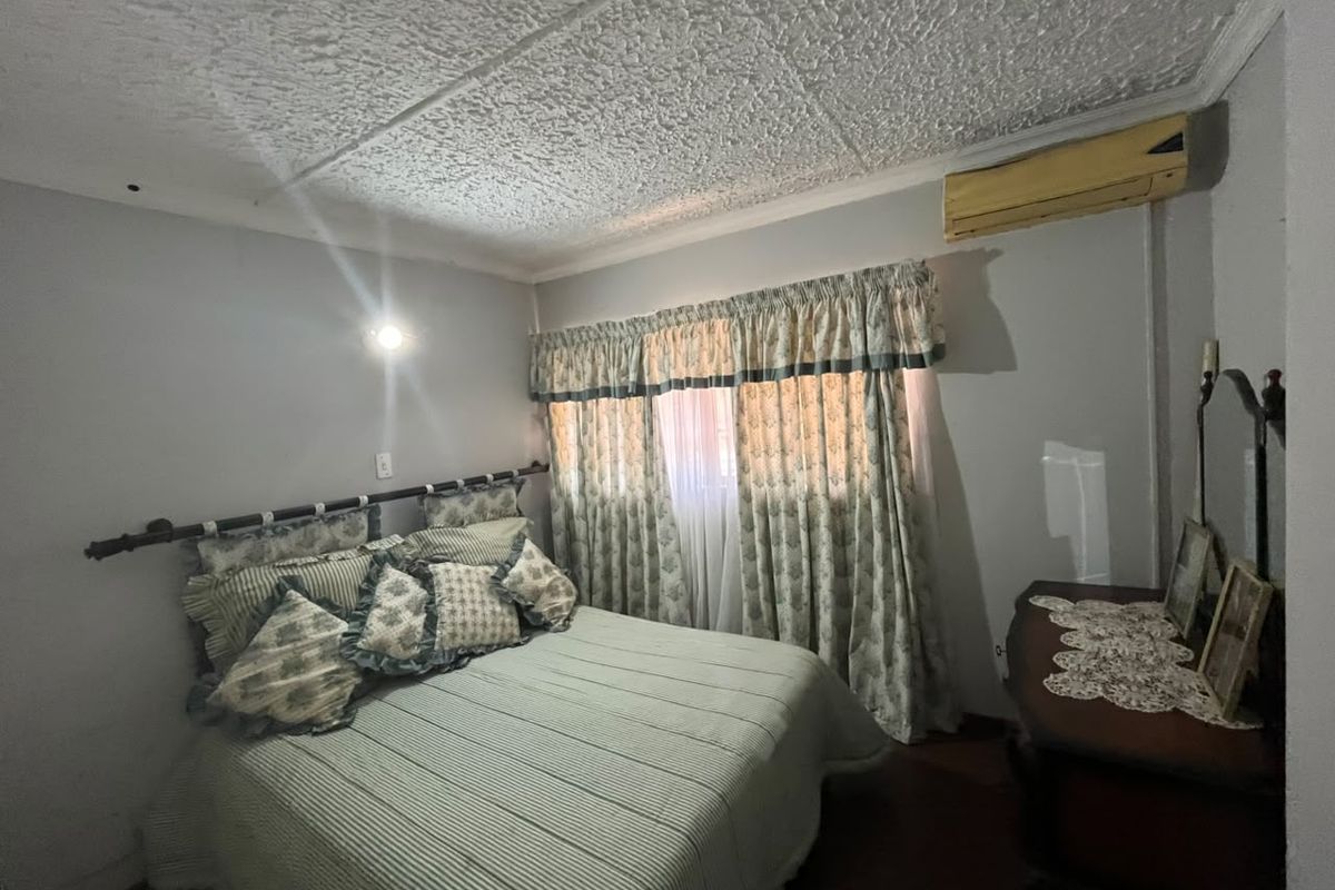 A bedroom featuring a textured ceiling, coving, and a wall-mounted air conditioning unit.