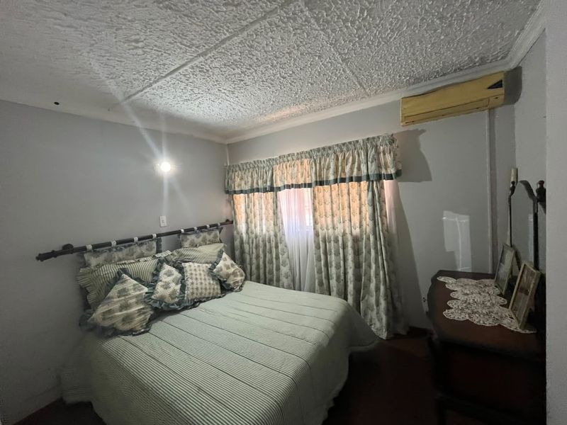 A bedroom featuring a textured ceiling, coving, and a wall-mounted air conditioning unit.