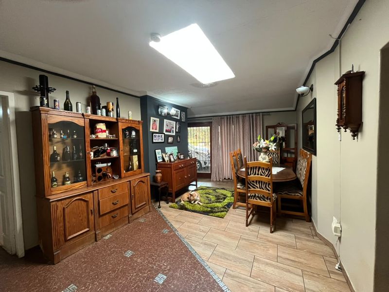 Dining area featuring tiled flooring, a large fluorescent light fixture, and direct access to the exterior through a glass panel door.