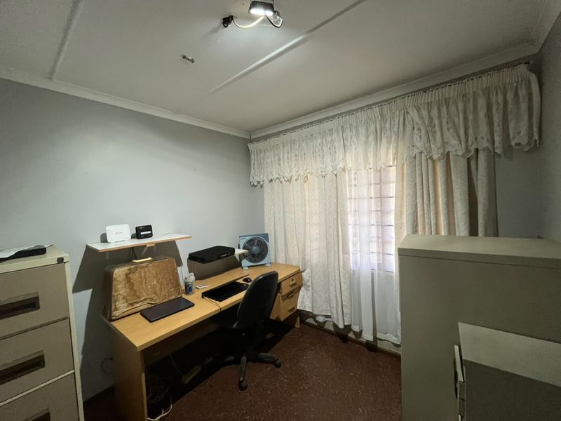A functional bedroom space featuring security bars on the window and basic finishes, suitable for renovation or restyling to enhance its appeal.