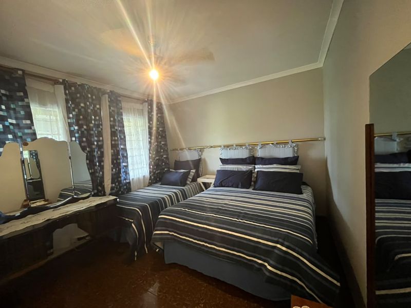 A bedroom featuring tiled flooring, coving, and a ceiling fan, providing a functional space with neutral wall finishes.