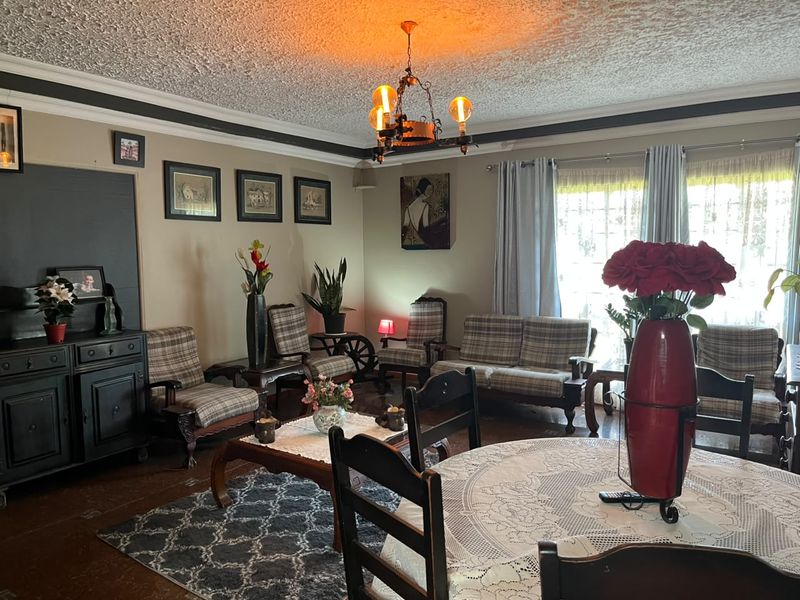 A traditional living room featuring a textured ceiling, crown molding, a central chandelier, and sliding glass doors providing natural light.