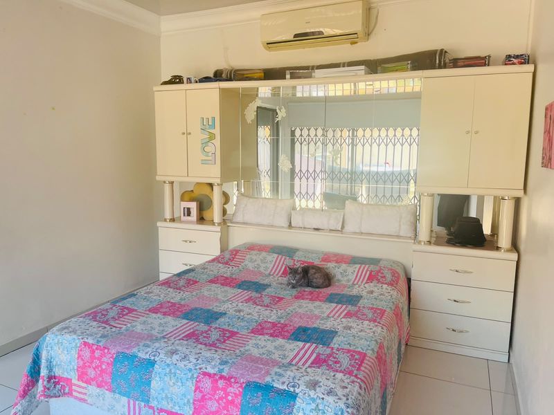 Bedroom featuring built-in cabinetry with integrated mirrored headboard and a wall-mounted air conditioning unit.