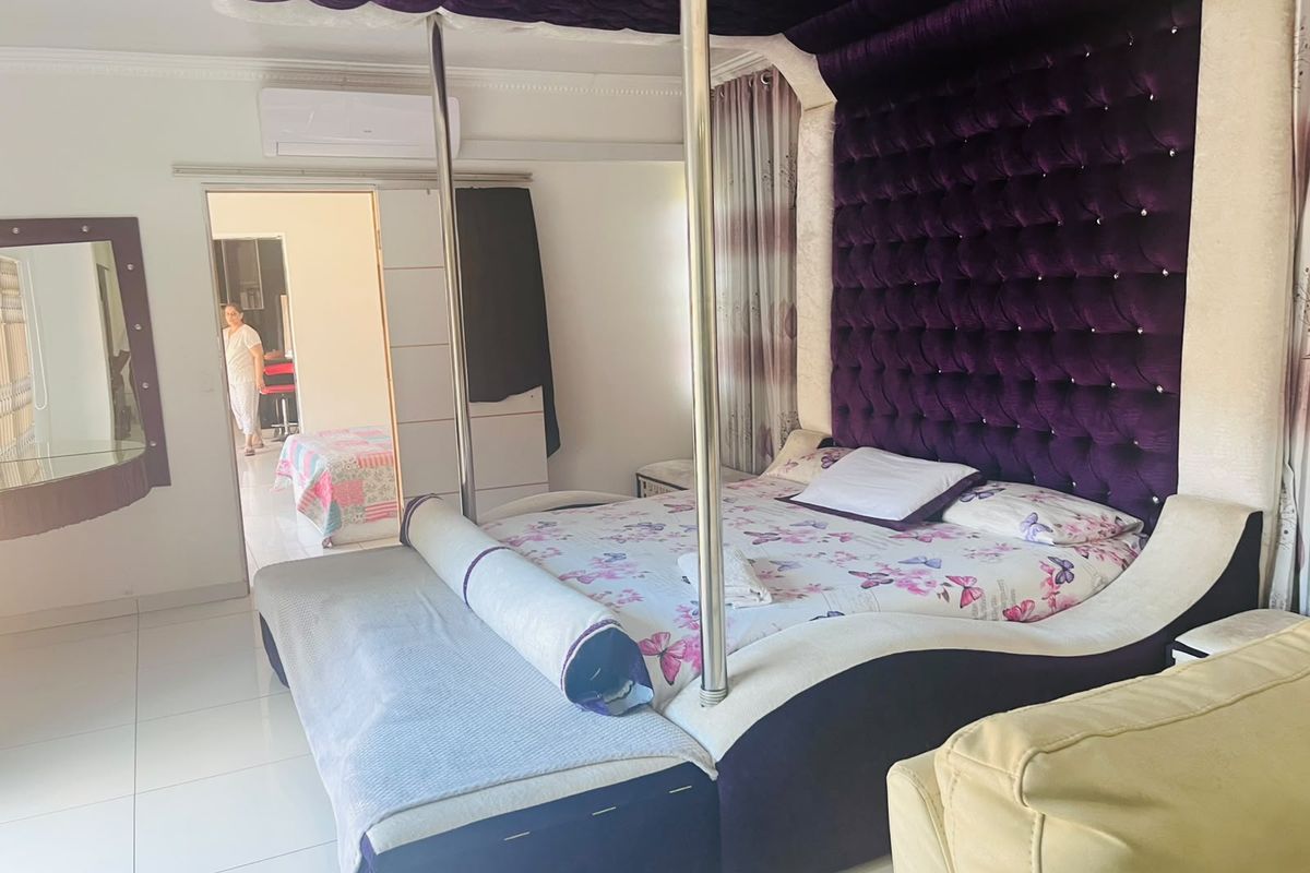 A spacious bedroom featuring tiled flooring, coving, and a wall-mounted split-system air conditioning unit.