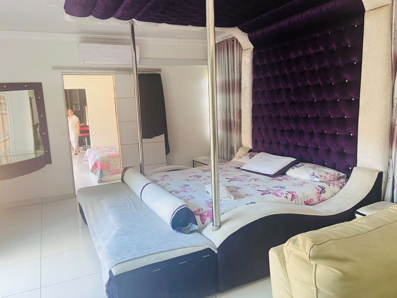 A spacious bedroom featuring tiled flooring, coving, and a wall-mounted split-system air conditioning unit.