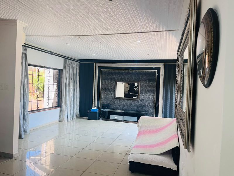 Spacious living room featuring tiled flooring, a textured ceiling with recessed lighting, and a prominent built-in feature wall.