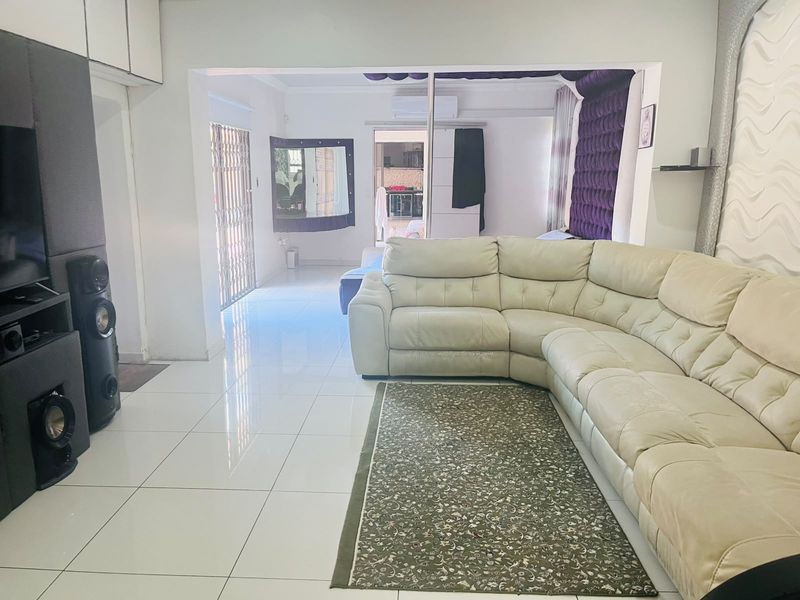 Spacious living area featuring polished tiled flooring, built-in storage, and an air conditioning unit, with an open flow to adjacent living spaces.