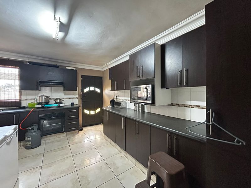 Functional kitchen featuring dark wood cabinetry, built-in oven, gas hob, and tiled flooring with ample storage space.
