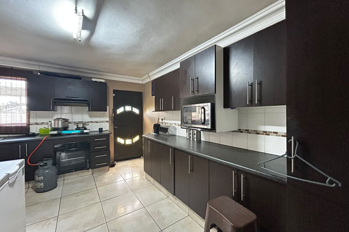 Functional kitchen featuring dark wood cabinetry, built-in oven, gas hob, and tiled flooring with ample storage space.