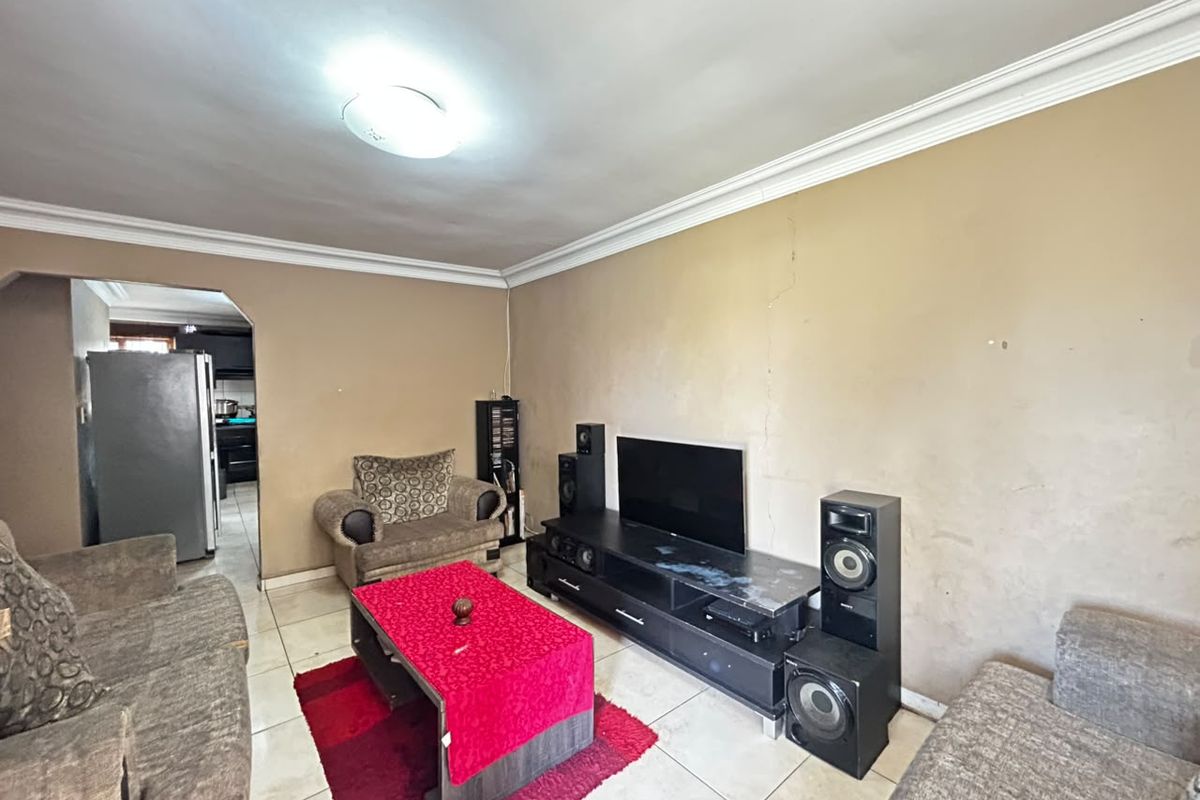 A living room featuring tiled flooring and ceiling cornicing, currently showing signs of wall surface wear and requiring cosmetic updates.
