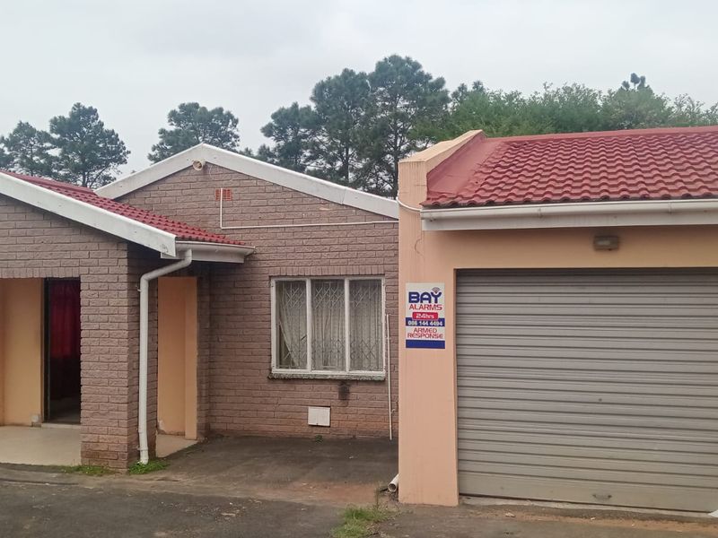 Front elevation of a single-story brick house featuring a tiled roof, integrated garage, and covered entrance area.