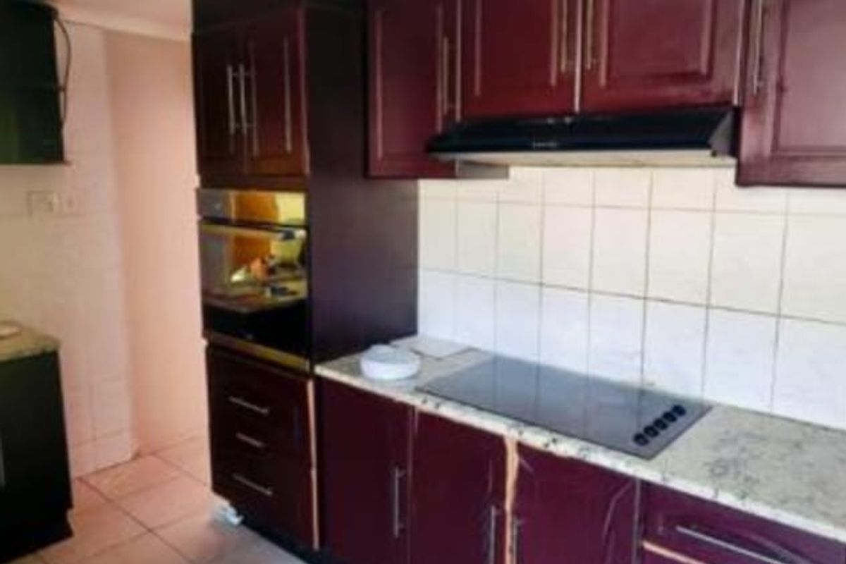 A dated kitchen featuring dark wood-finish cabinetry, built-in oven, ceramic hob, and tiled backsplash, requiring cosmetic updates to improve its aesthetic appeal.