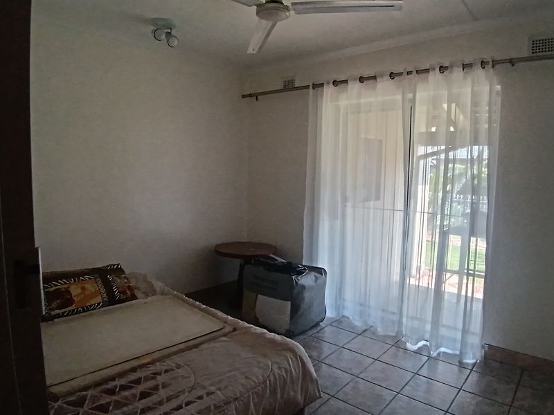 A bedroom featuring tiled flooring, a ceiling fan, and a sliding glass door providing access to the exterior.