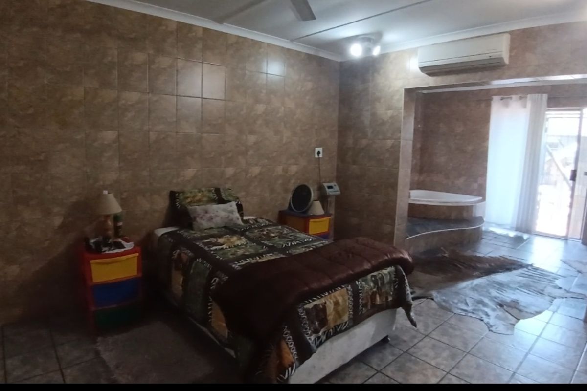 Bedroom featuring extensive wall tiling, a split-system air conditioner, and an integrated corner bathtub area with direct access to an outdoor space.