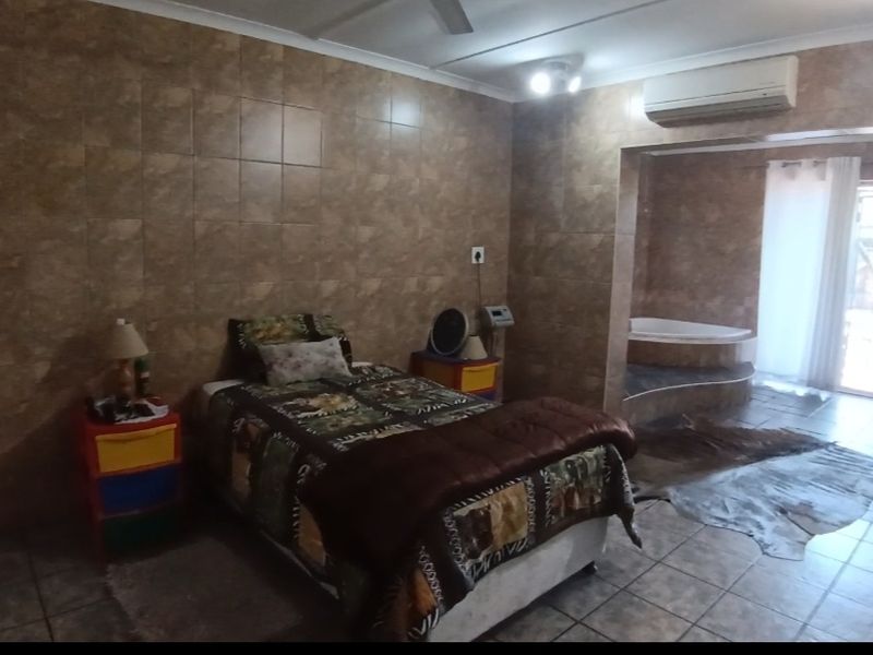 Bedroom featuring extensive wall tiling, a split-system air conditioner, and an integrated corner bathtub area with direct access to an outdoor space.