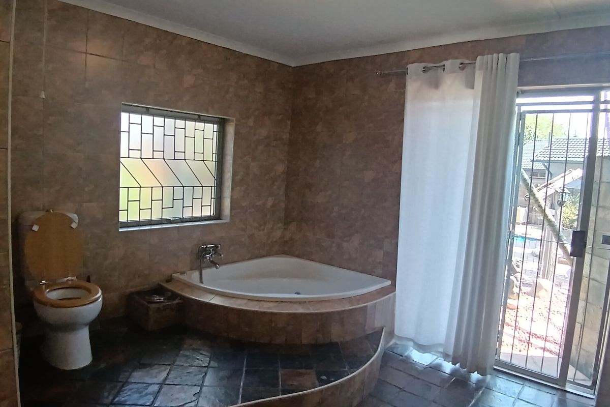 A spacious bathroom featuring a corner bathtub, tiled walls and flooring, and direct access to the outdoor area through a sliding door.