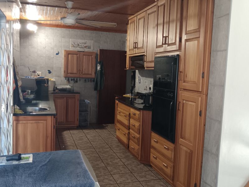 A functional kitchen featuring extensive wooden cabinetry, built-in oven, tiled backsplash, and tiled flooring, offering a traditional aesthetic with potential for modernization.