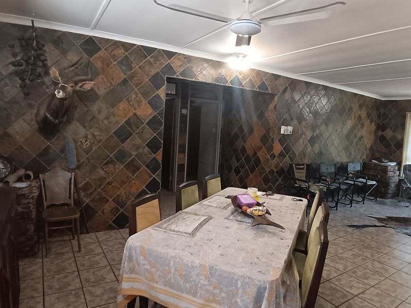Dining area featuring distinctive dark slate tile wall cladding, ceramic floor tiles, and a central ceiling fan.