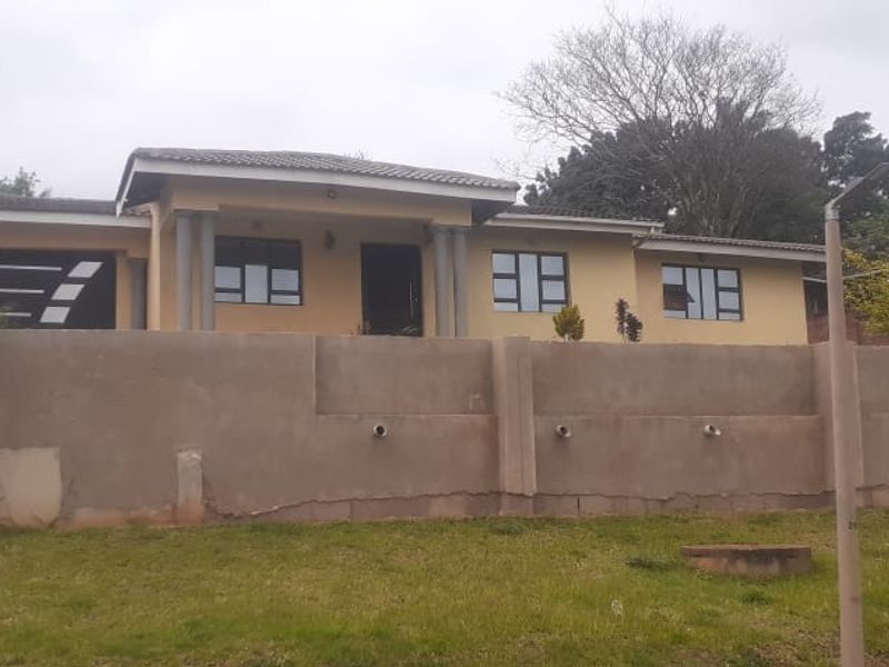 Front elevation of a single-story house featuring a double garage, tiled roof, and a prominent concrete boundary wall requiring maintenance.