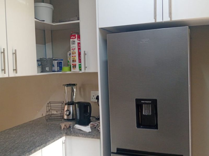 A functional kitchen area featuring white built-in cabinetry and a grey laminate countertop, providing essential storage and workspace.