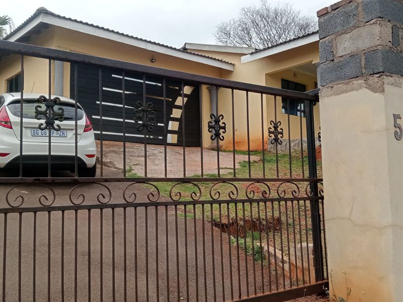 Front view of a residential property featuring a wrought iron gate, concrete driveway, and garage access.