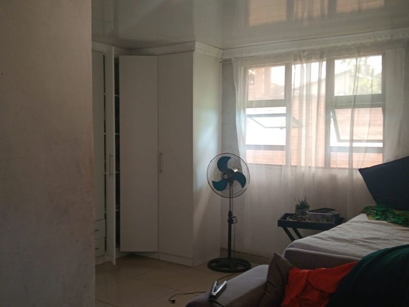 A bedroom featuring built-in cupboards, tiled flooring, and a glossy ceiling finish.