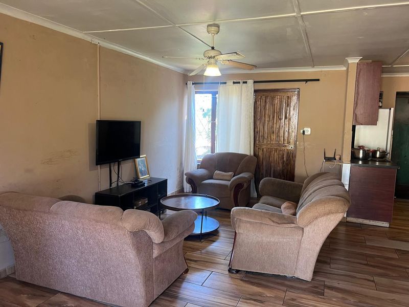 Open plan living area featuring tiled flooring, a ceiling fan, and direct access to the kitchen space.
