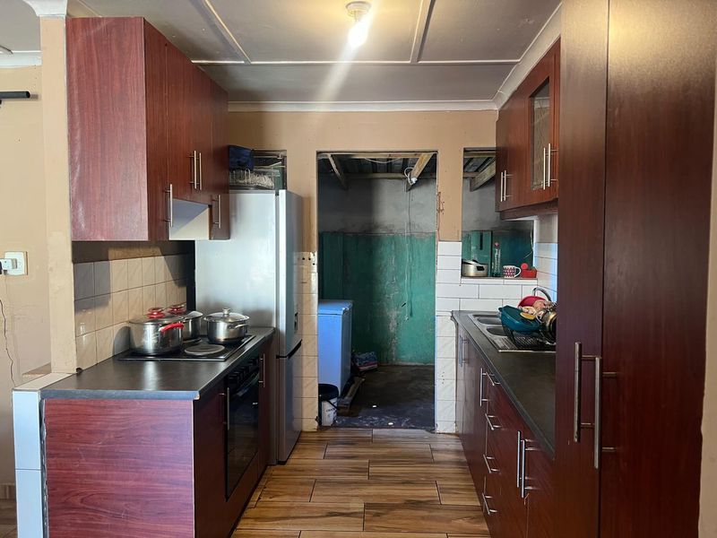 A functional kitchen featuring dark wood-look cabinetry, laminate countertops, and a built-in oven, requiring cosmetic updates to improve the overall finish.