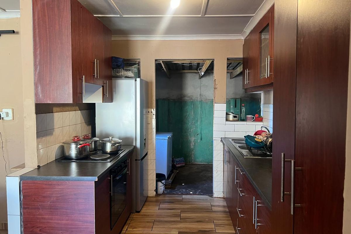 A functional kitchen featuring dark wood-look cabinetry, laminate countertops, and a built-in oven, requiring cosmetic updates to improve the overall finish.