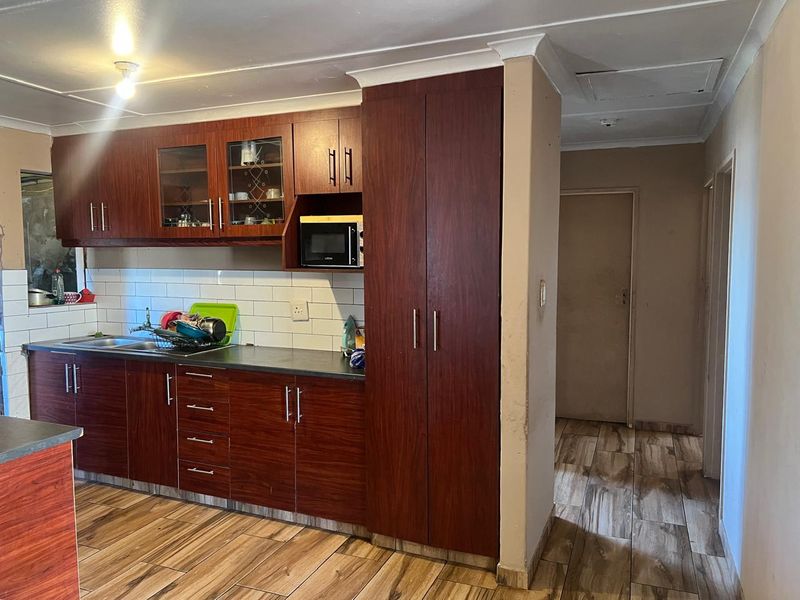 A functional kitchen featuring dark wood-look cabinetry, tiled backsplash, and durable tiled flooring, providing a practical workspace with integrated storage.