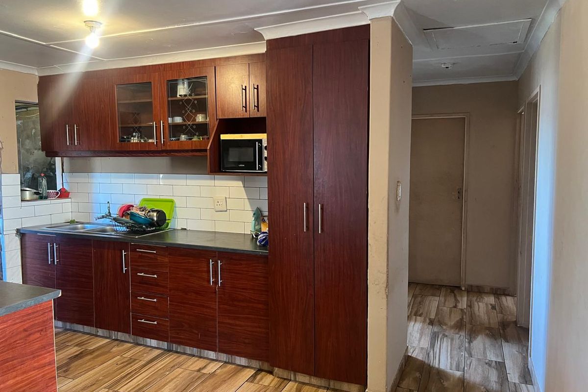 A functional kitchen featuring dark wood-look cabinetry, tiled backsplash, and durable tiled flooring, providing a practical workspace with integrated storage.