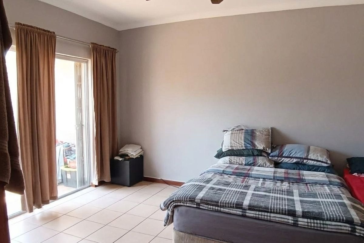 A bedroom featuring tiled flooring, a ceiling fan, and a sliding glass door providing access to an outdoor area.