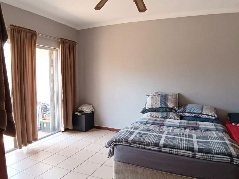 A bedroom featuring tiled flooring, a ceiling fan, and a sliding glass door providing access to an outdoor area.