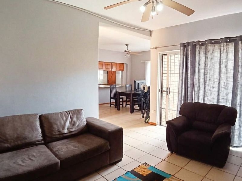 Open-plan living and dining area featuring tiled flooring, a ceiling fan, and direct access to an outdoor space through a sliding glass door.