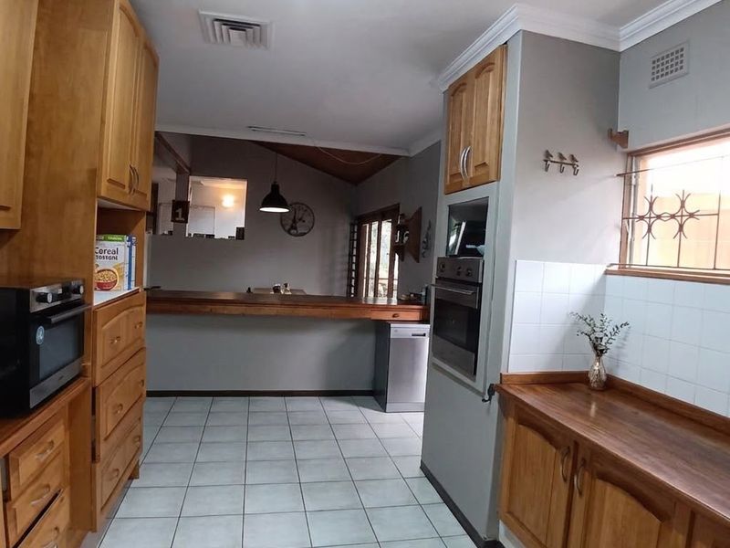 A functional kitchen featuring wooden cabinetry, wooden countertops, built-in oven, and a breakfast bar overlooking the adjacent living area.
