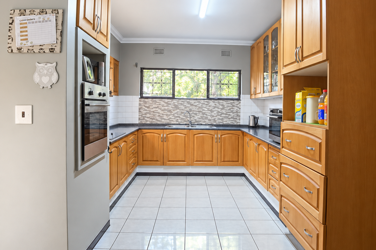 A functional U-shaped kitchen featuring warm-toned wooden cabinetry, tiled flooring, a built-in oven, and a tiled backsplash with ample storage space.