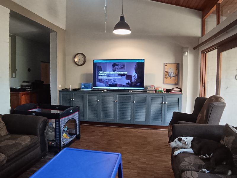 Spacious living room featuring a vaulted timber ceiling, parquet flooring, built-in cabinetry, and large sliding glass doors providing natural light.