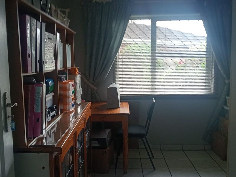 A functional home office space featuring tiled flooring and a window with fitted blinds, providing natural light.