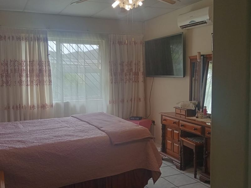 A bedroom featuring tiled flooring, a ceiling fan, and a wall-mounted split-system air conditioner.