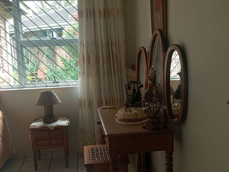 A bedroom featuring tiled flooring, security bars on the window, and an aluminium window frame, offering a functional and well-lit space.